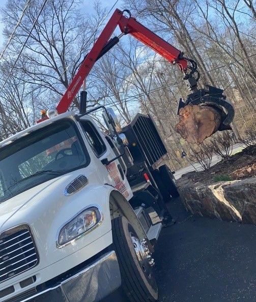 White truck with red crane arm lifting a large log.