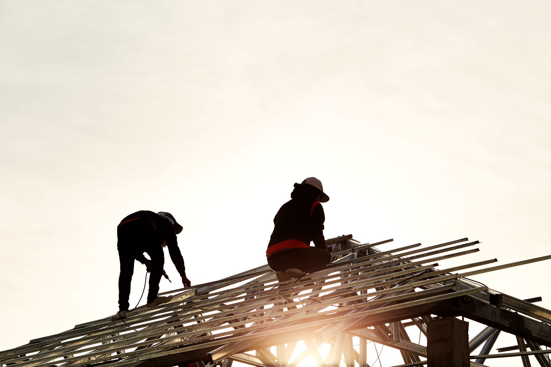 Two construction workers are working on the roof of a building.