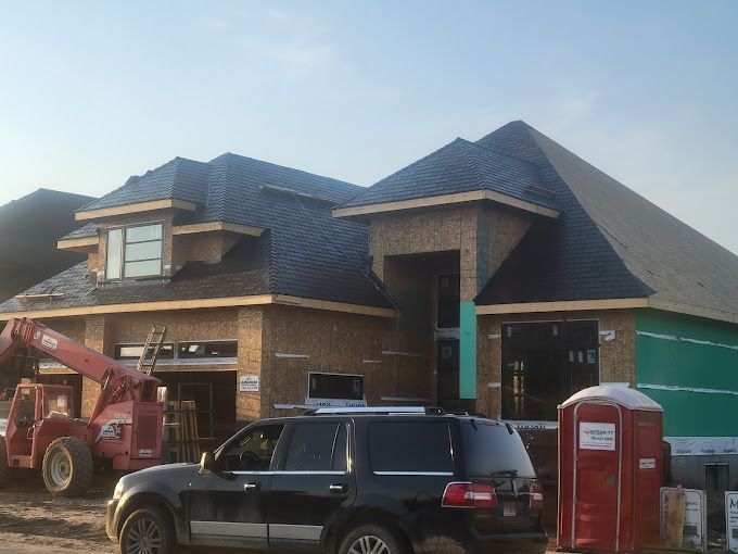 A black suv is parked in front of a house under construction