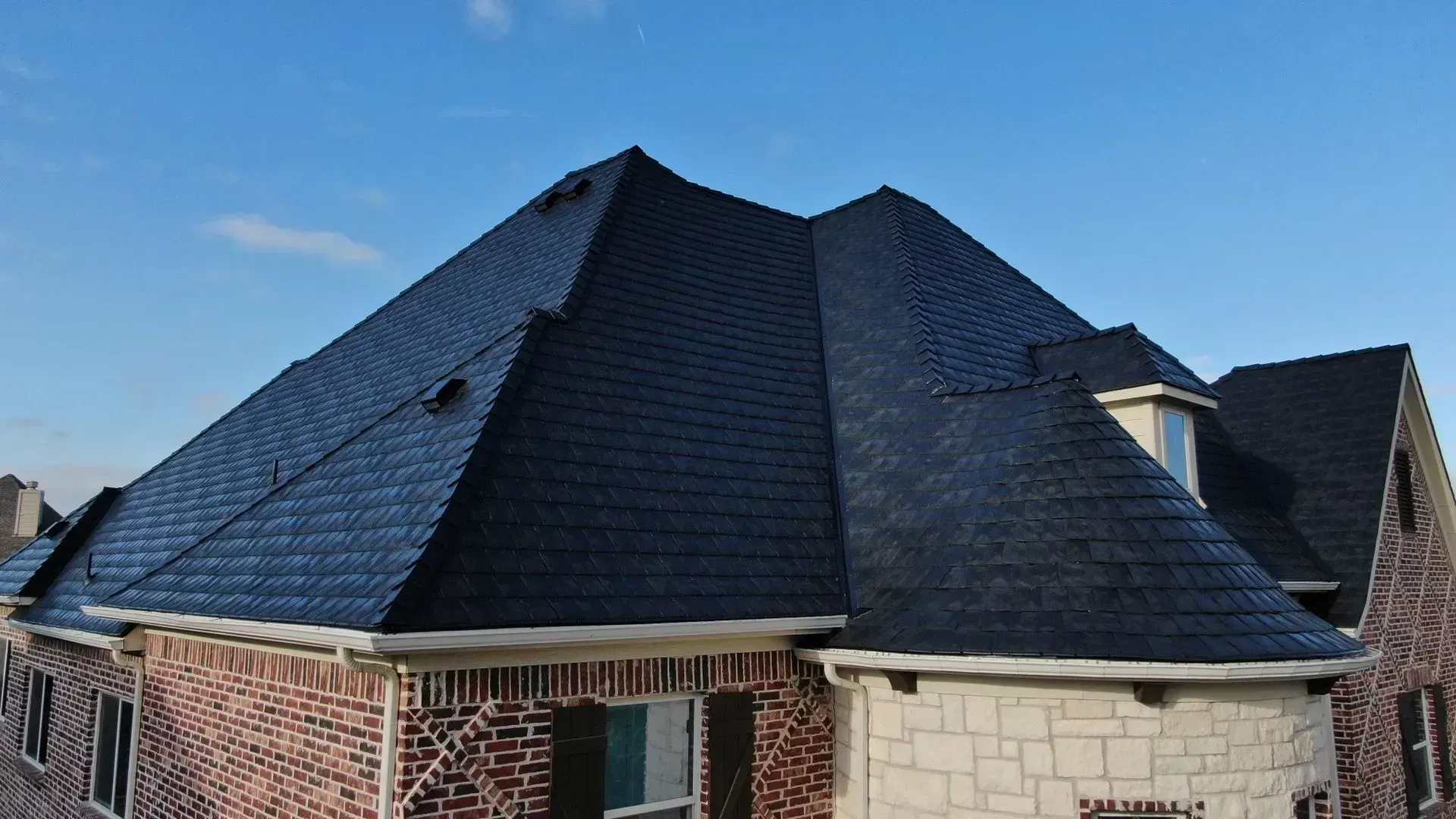 A man wearing a hard hat is using a drill on a roof