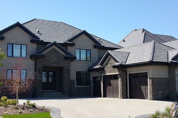 A large house with a gray roof and brown garage doors