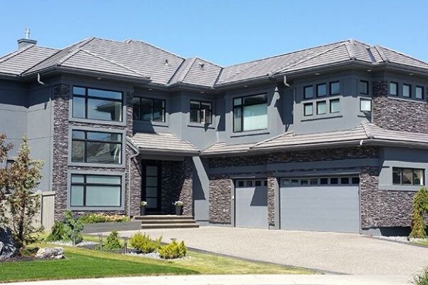 A large gray house with a garage and a lot of windows.