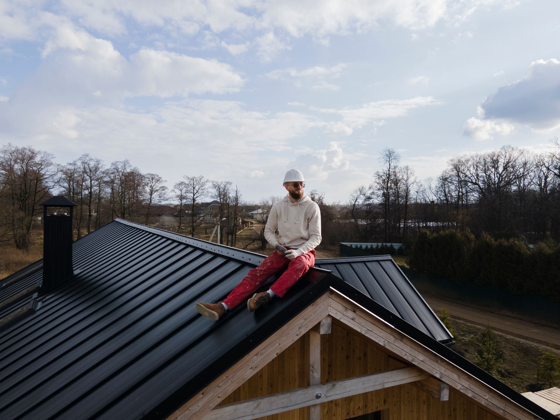 A man is sitting on the roof of a house.