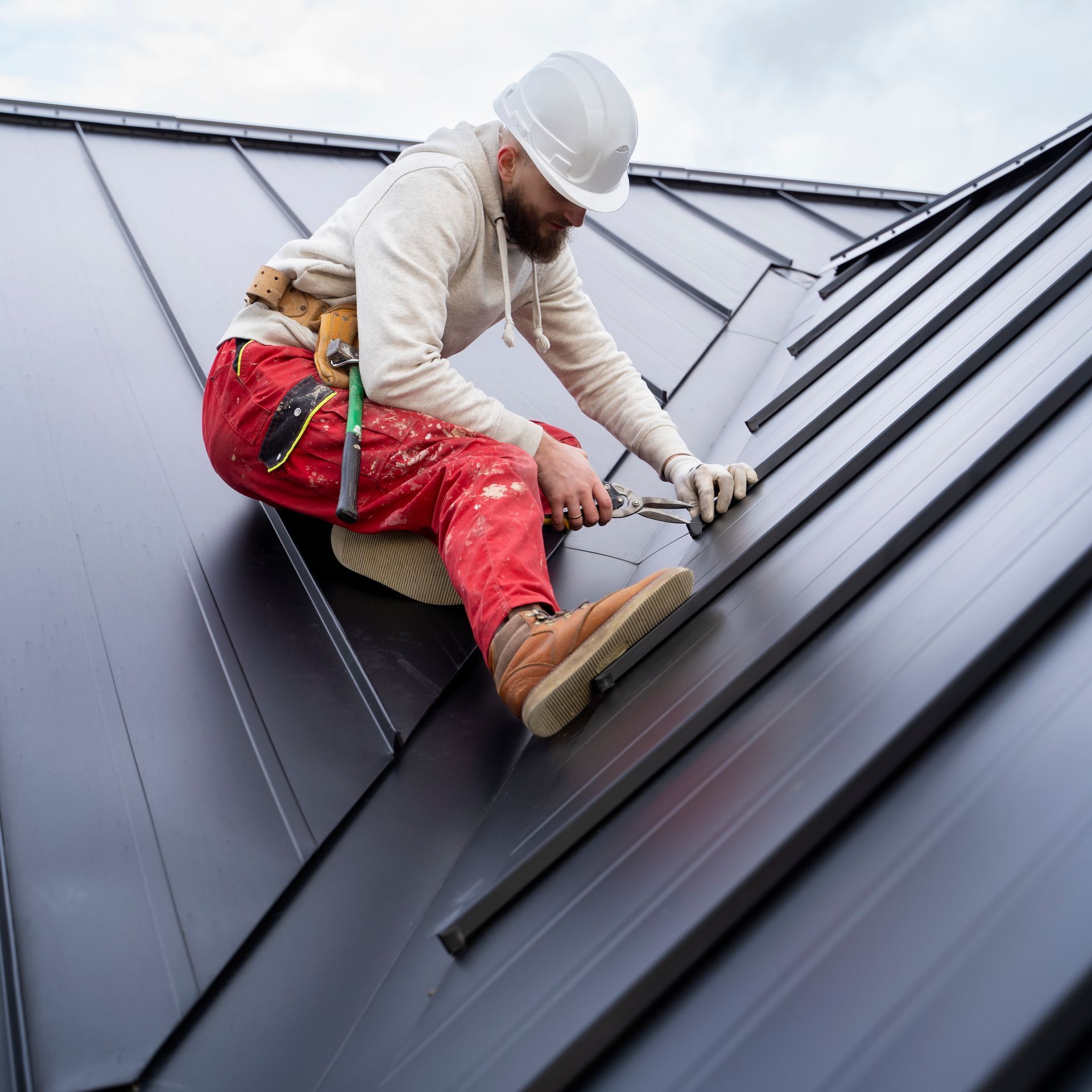 A man wearing a hard hat is working on a roof.