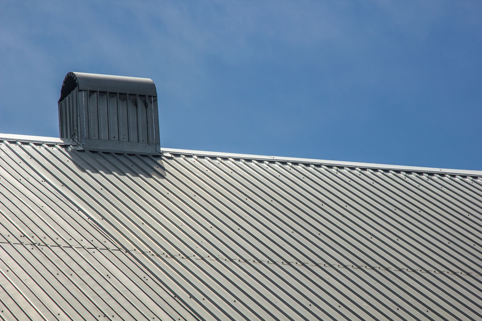 A roof with a chimney on it and a blue sky in the background