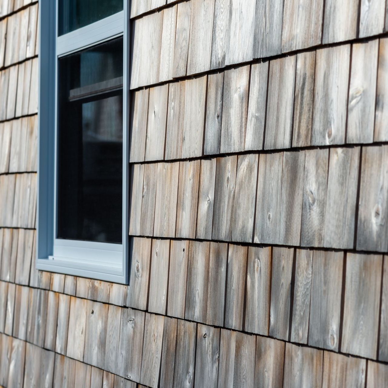 A close up of a wooden siding on a building with a window.