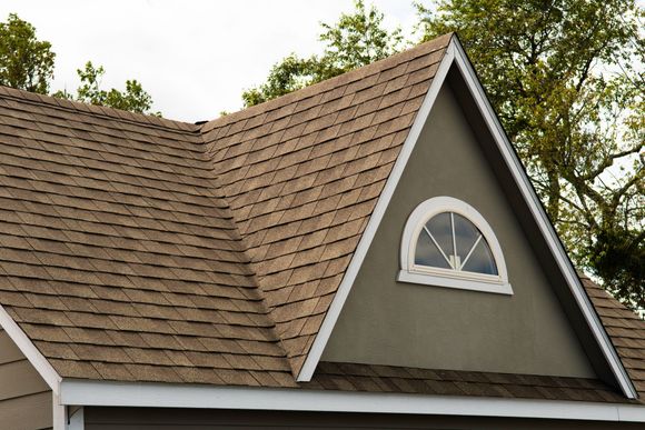 A brick house with a black roof and a chimney.