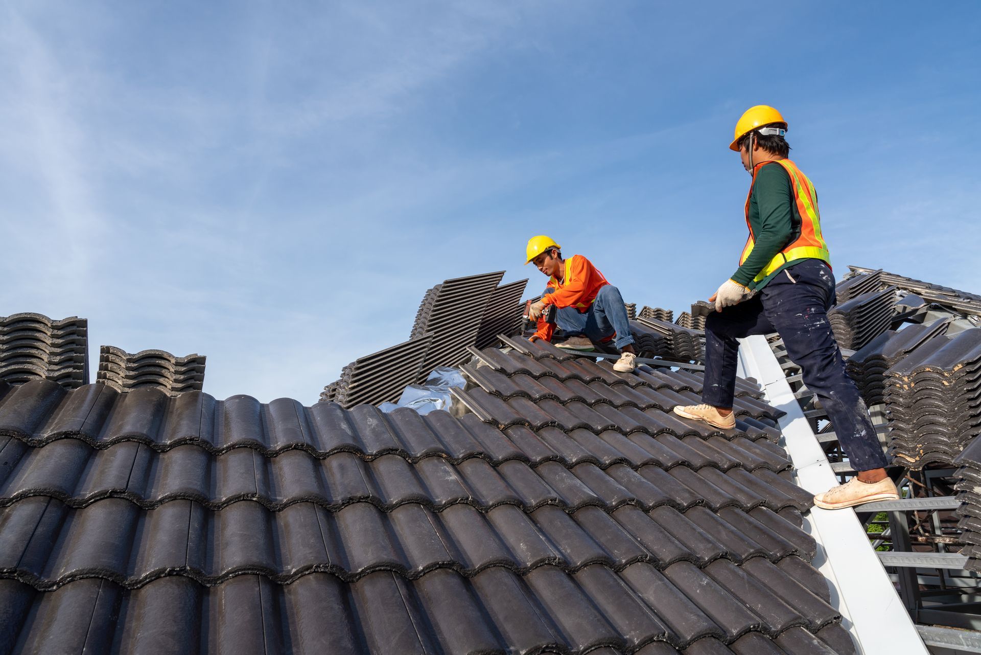 A man is kneeling on top of a tiled roof.