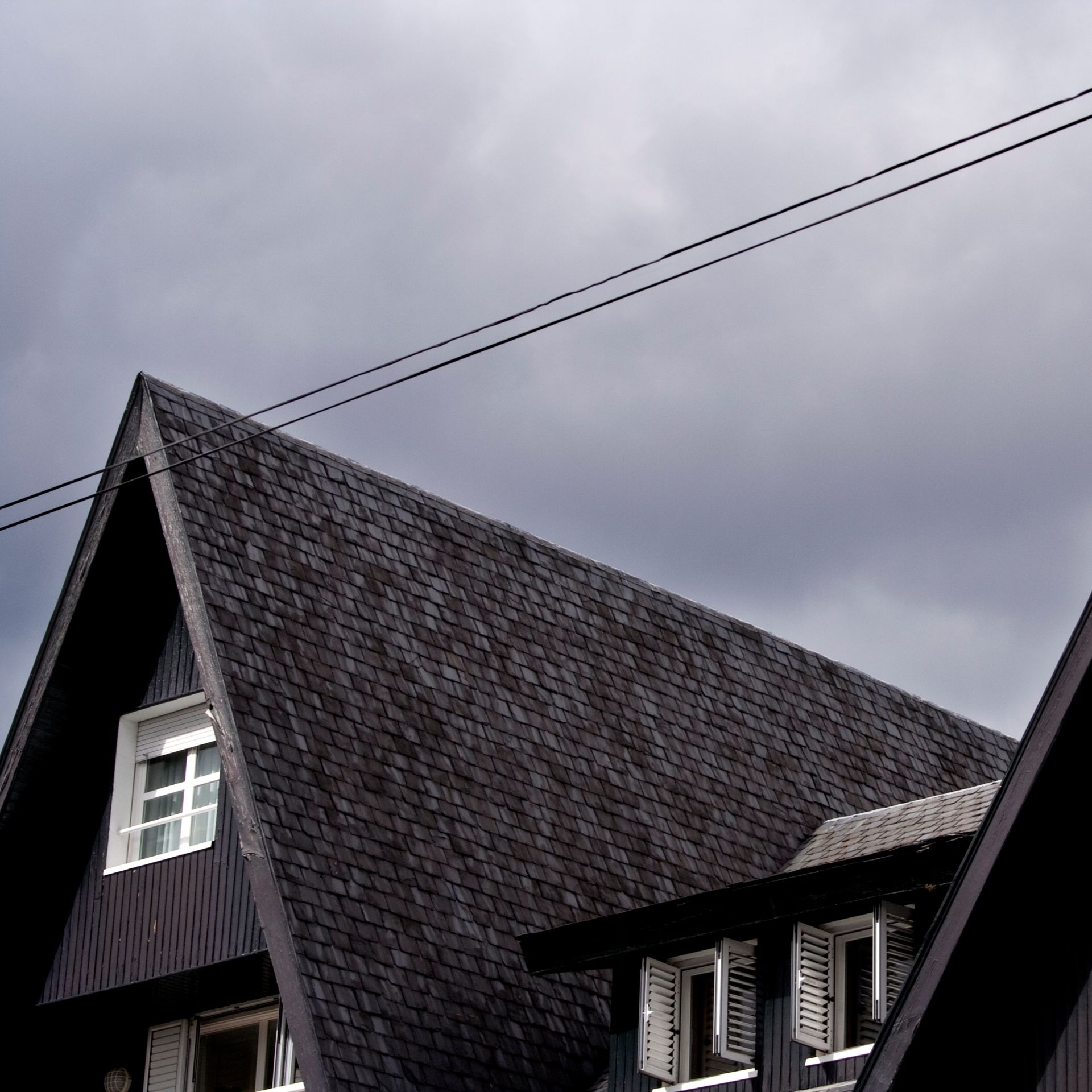 A roof of a house with a cloudy sky in the background