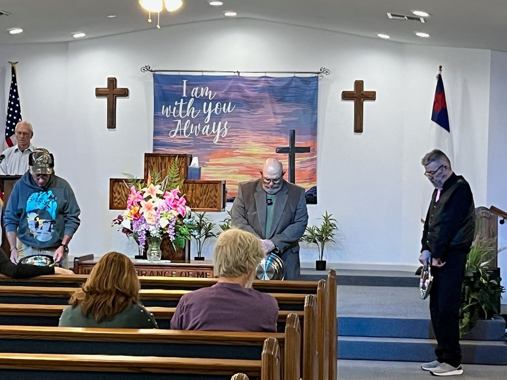 A group of people standing in prayer in a church sanctuary, with a banner reading 