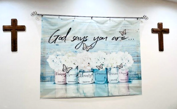 A banner on a white wall between two wooden crosses reads 