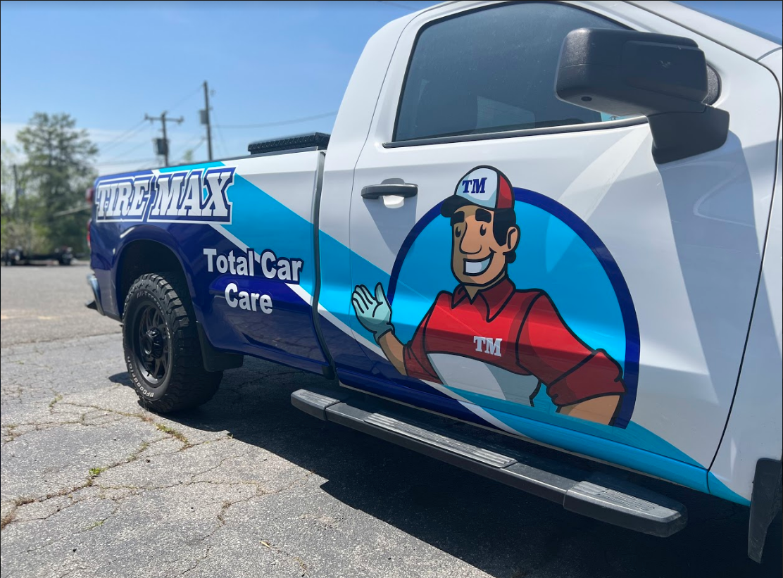 Truck wrap for tire supplier. Wrap has a man in a hat, smiling and waving and blue stripes.