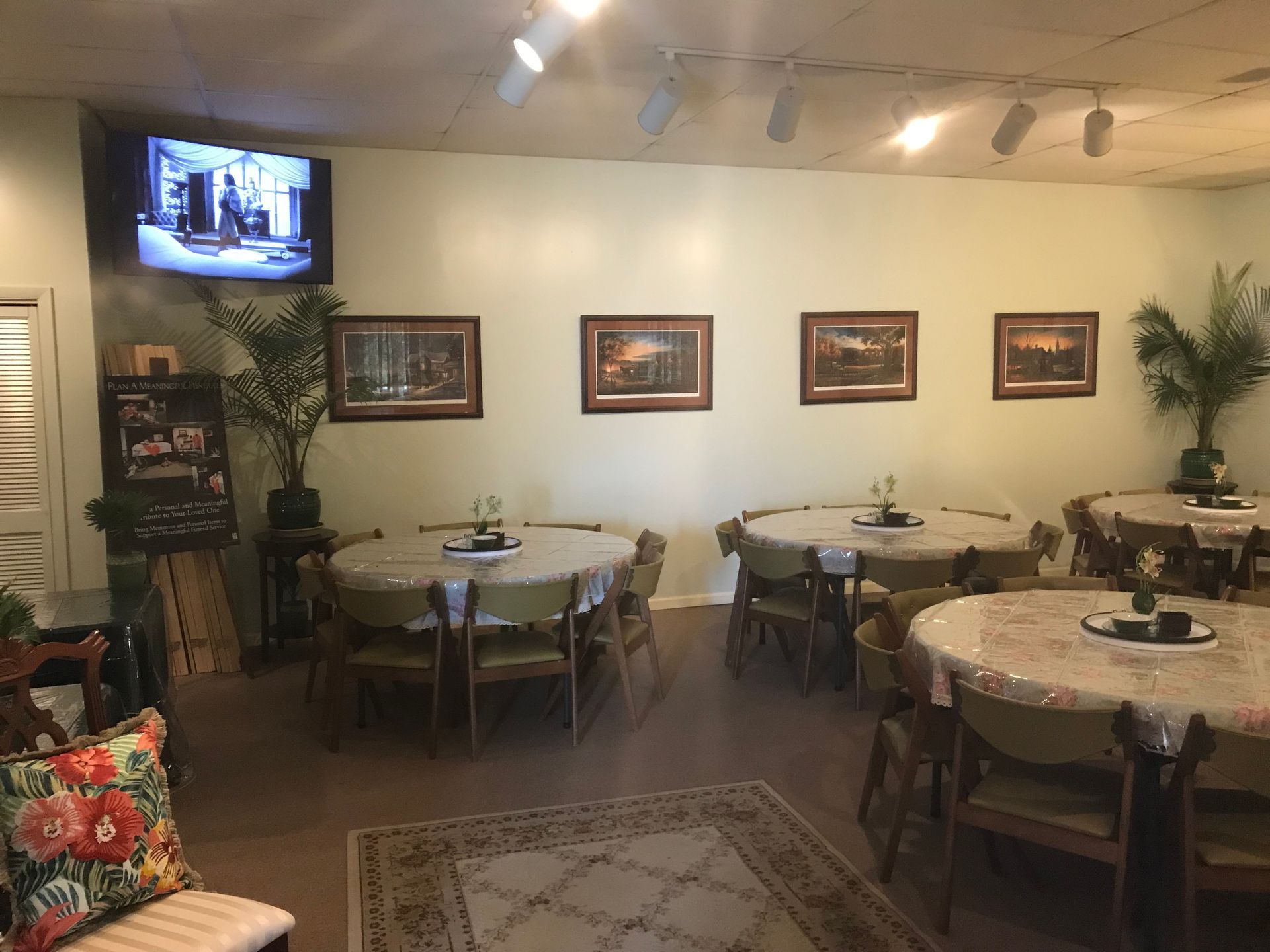 A dining room with tables and chairs and a television on the wall.