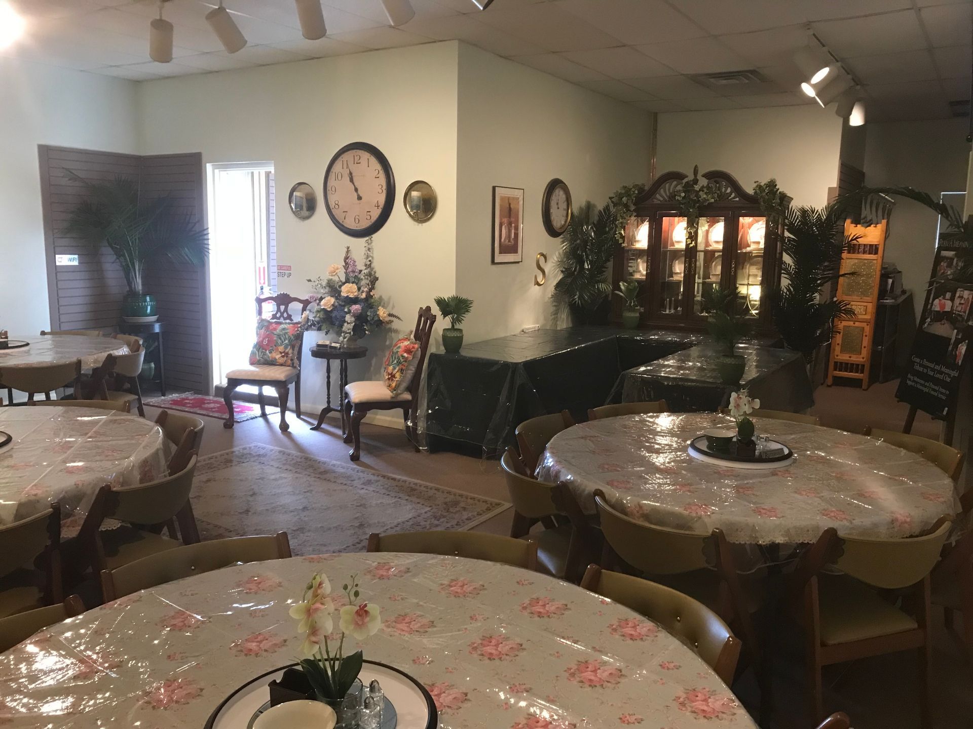 A room with tables and chairs and a clock on the wall.