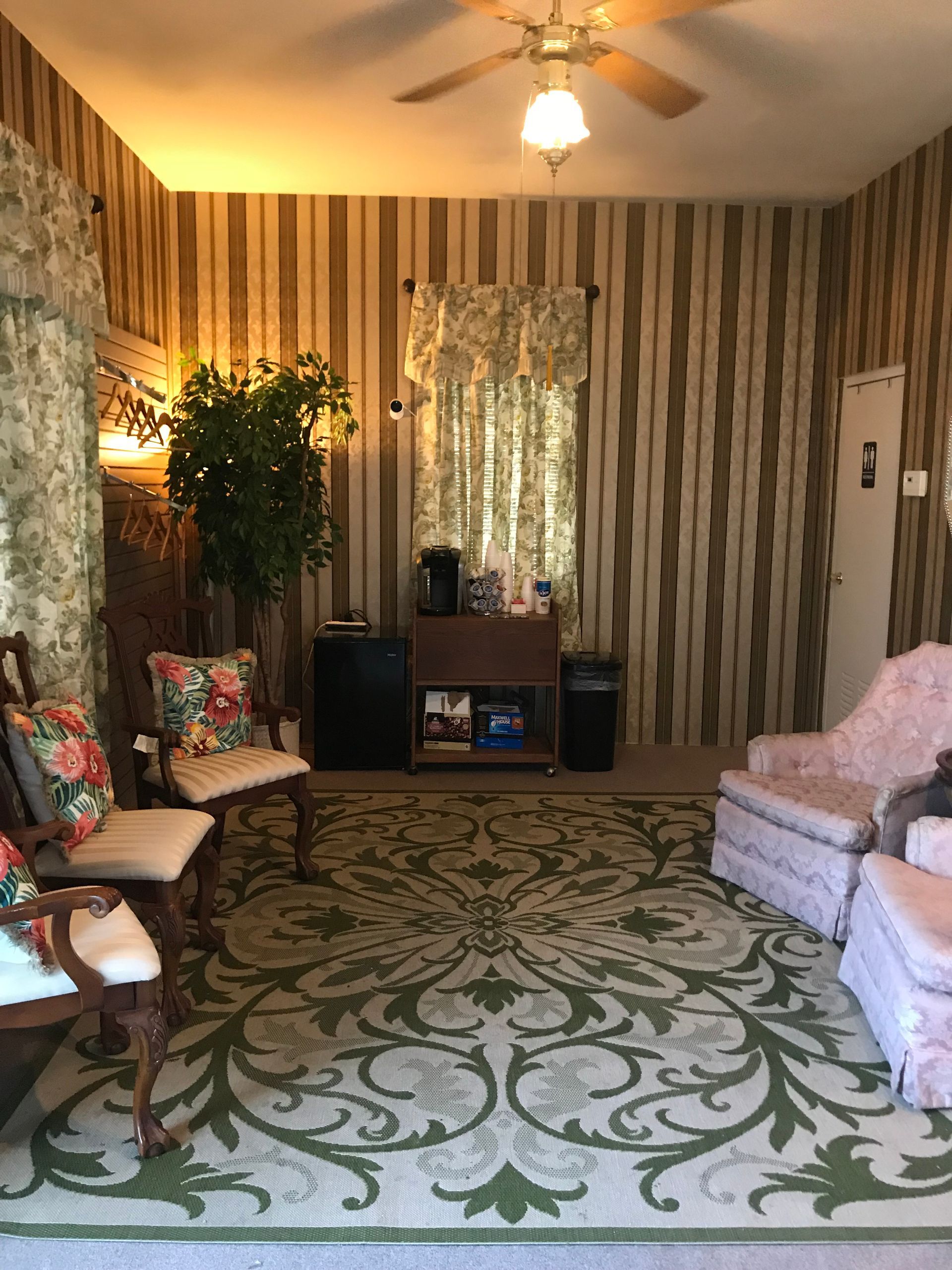 A living room with a rug , chairs , and a ceiling fan.