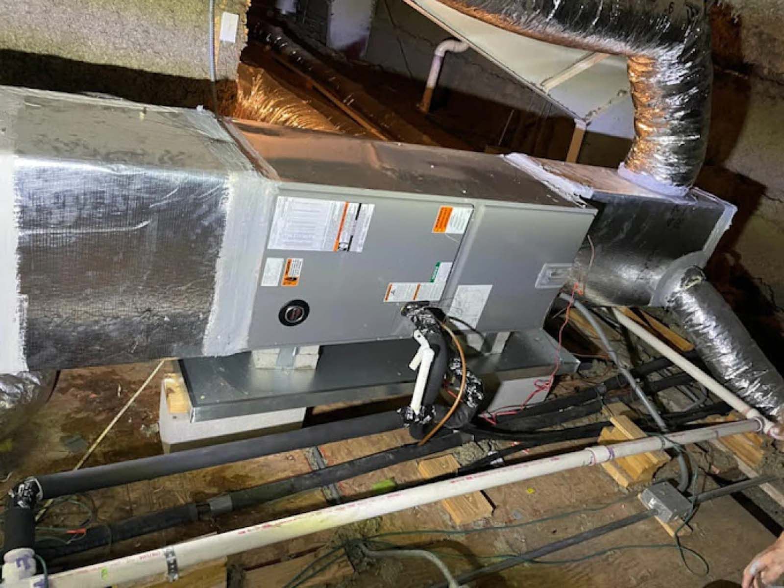 A person is working on an air conditioner in a basement.