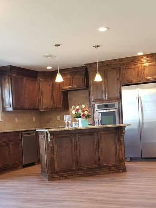 A kitchen with wooden cabinets , stainless steel appliances , and a large island.