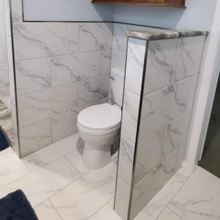 A bathroom with marble tiles and a toilet in the corner.