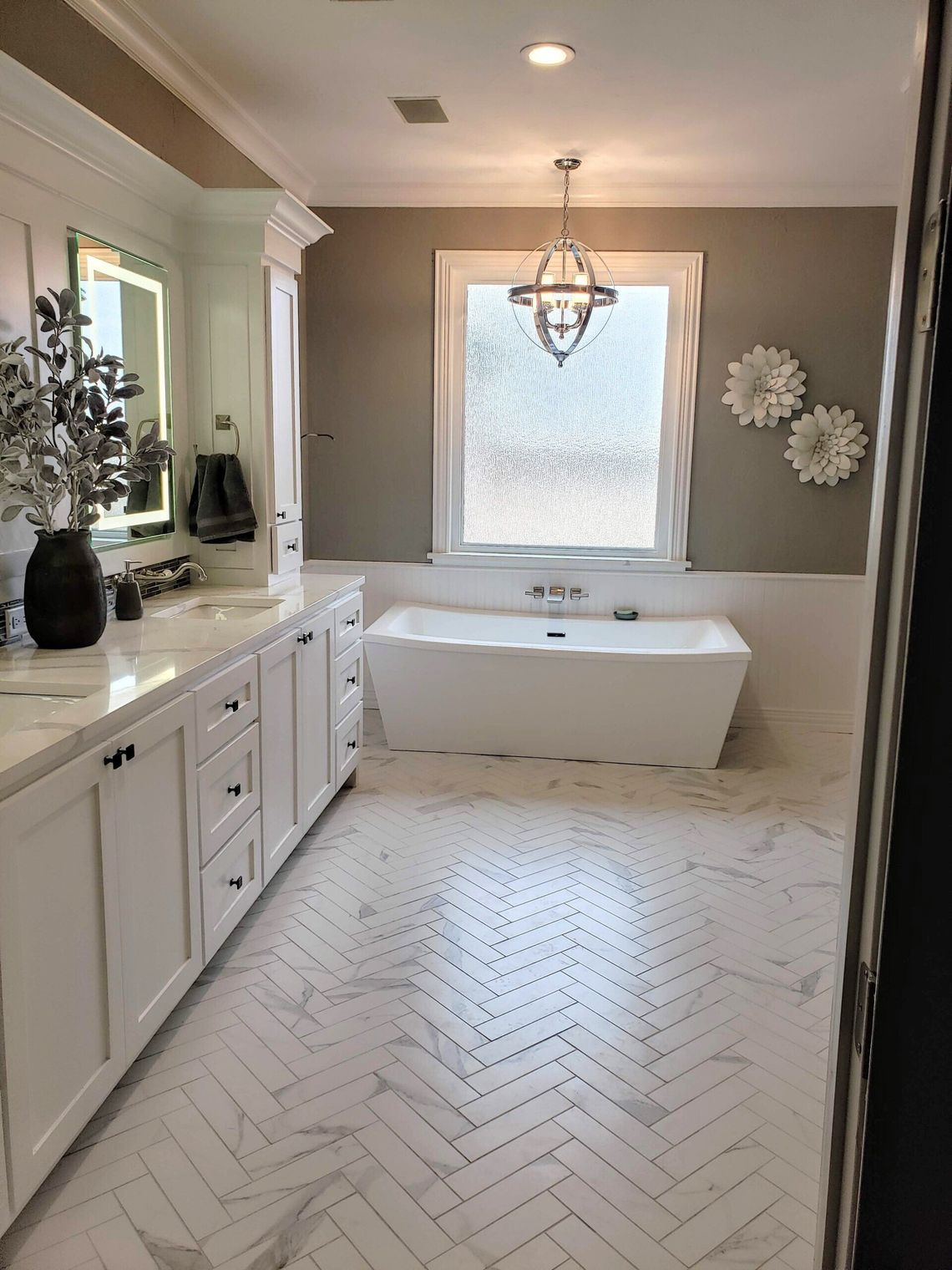 A bathroom with a tub , sink , mirror and window.