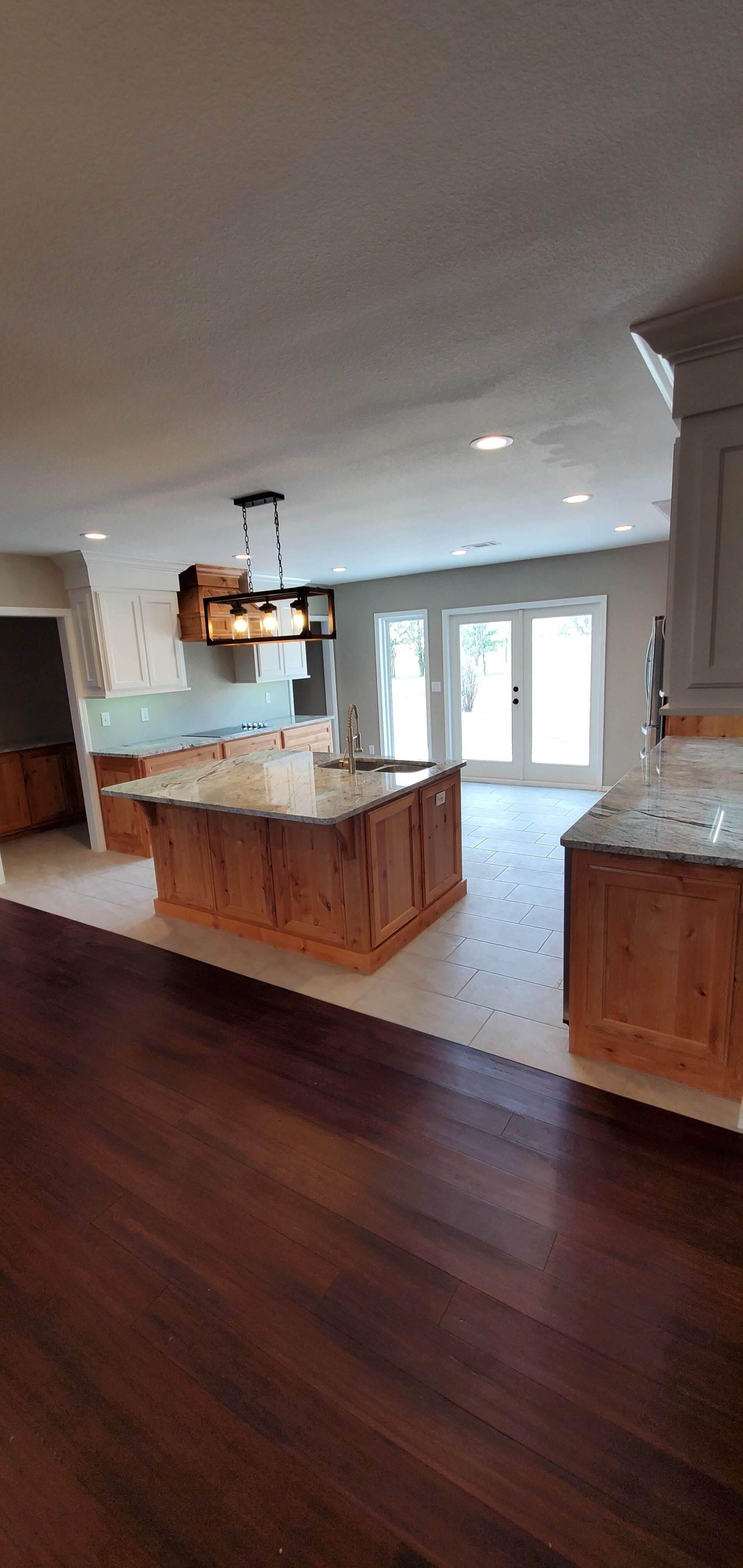 A kitchen with wooden cabinets , granite counter tops , and sliding glass doors.