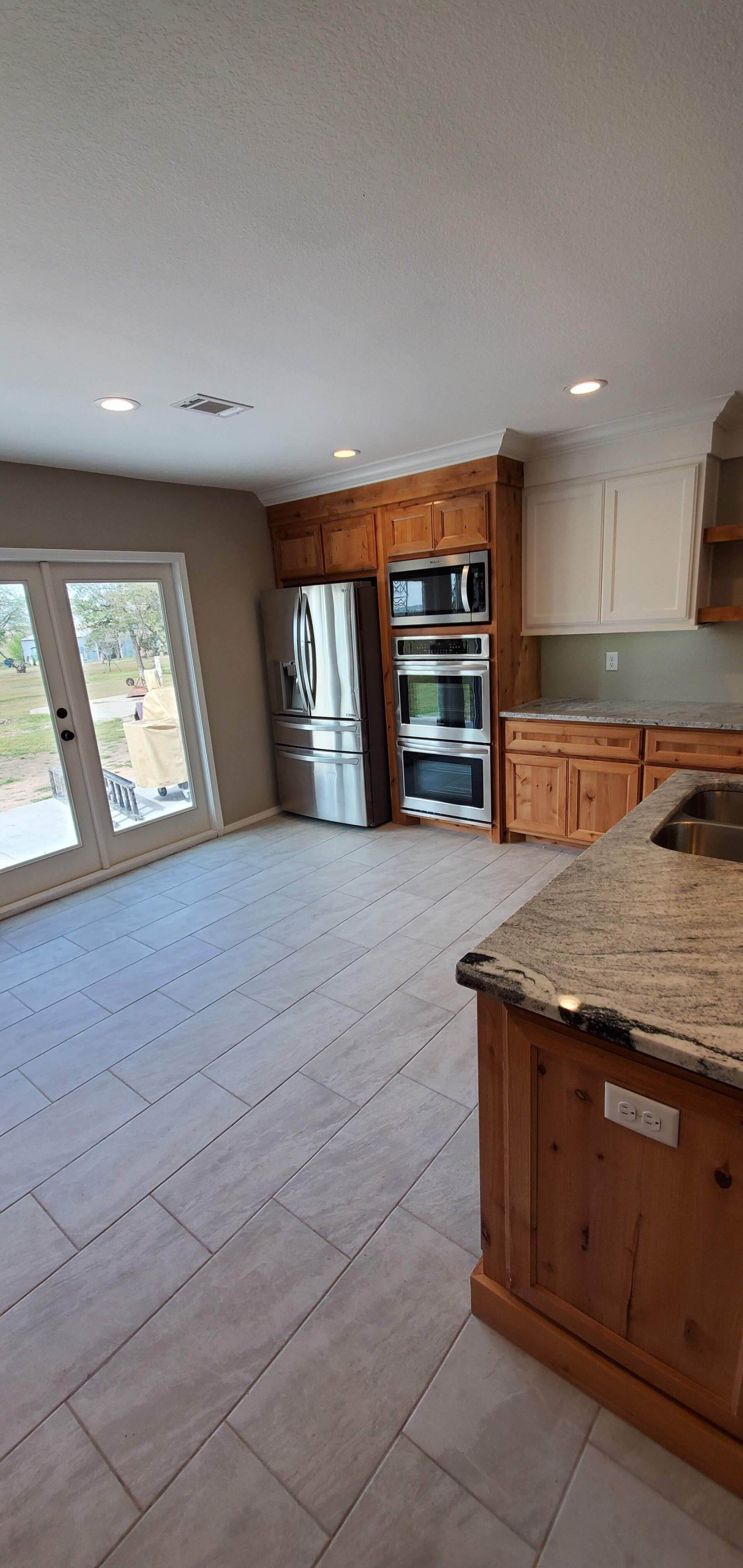 A kitchen with wooden cabinets , granite counter tops , stainless steel appliances , and a refrigerator.