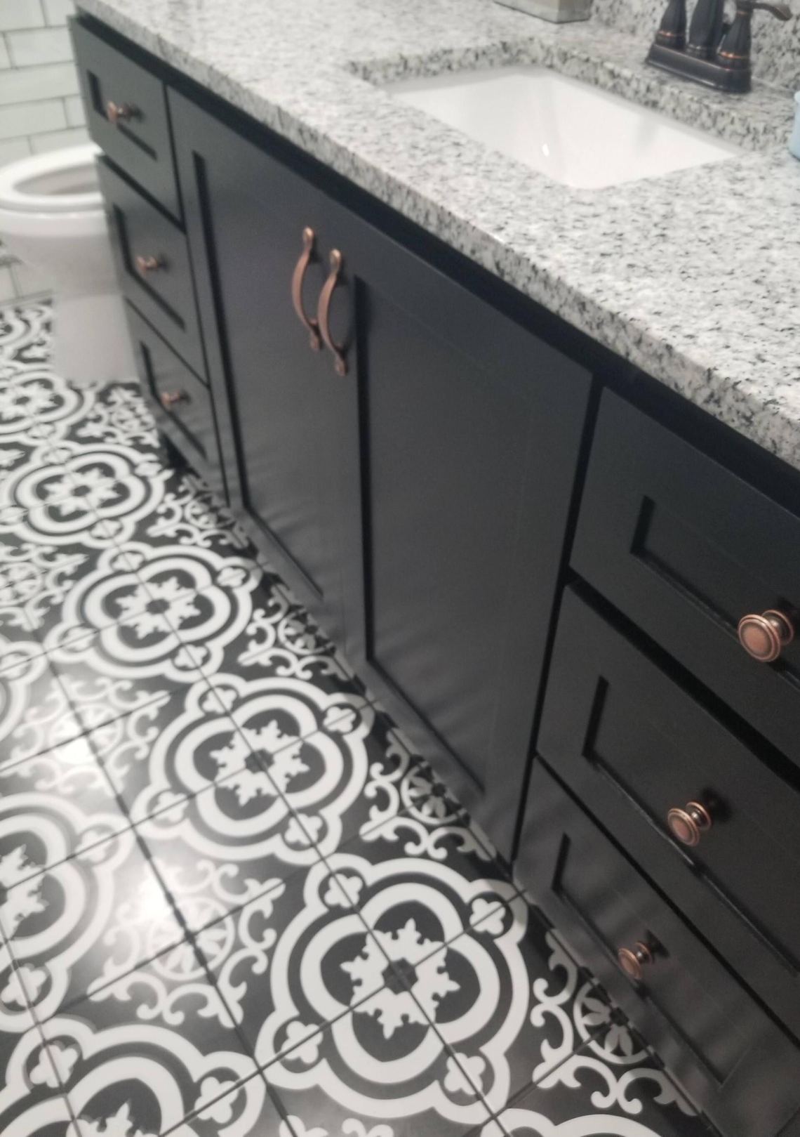 A bathroom with black cabinets and a black and white tile floor