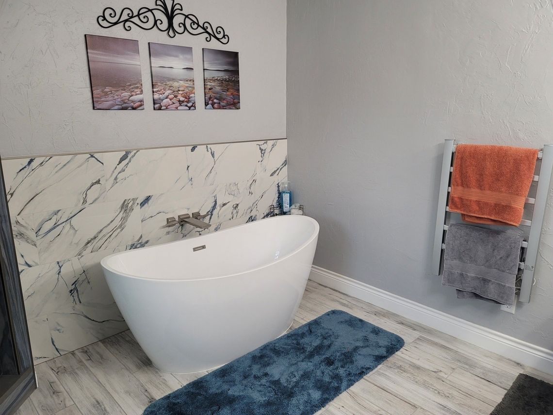 A bathroom with a bathtub , towel rack , and pictures on the wall.