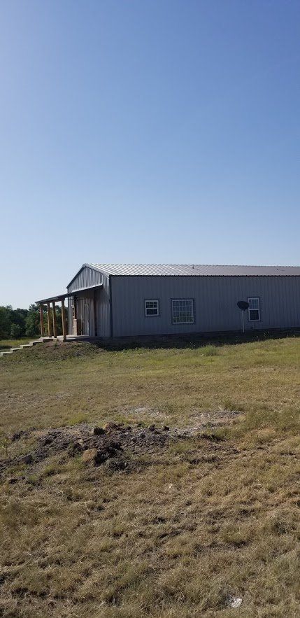 A large metal building is sitting in the middle of a grassy field.