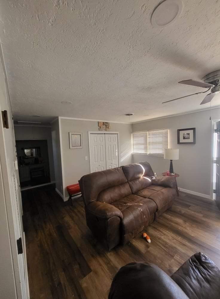 A living room with a brown couch and a ceiling fan.