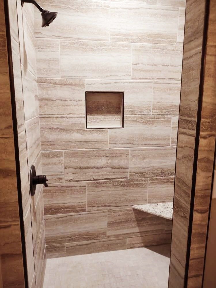 A bathroom with a walk in shower and a bench.