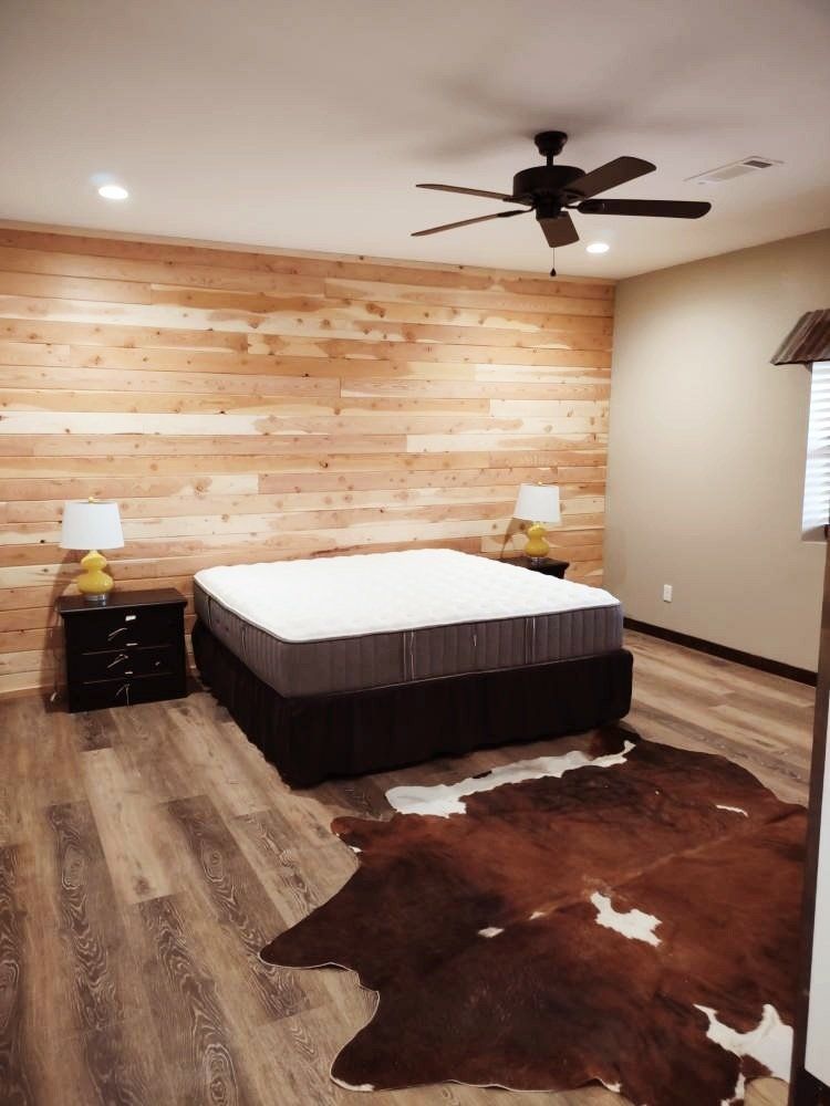 A bedroom with a cowhide rug and a ceiling fan.