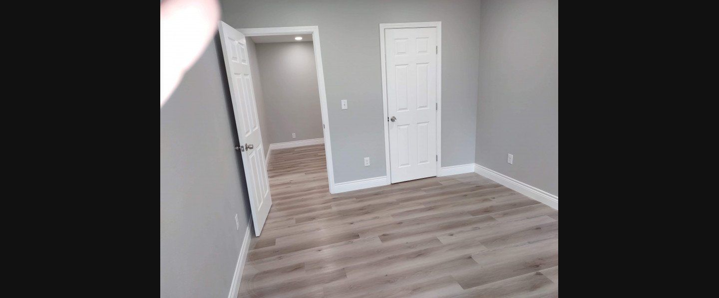 An empty room with hardwood floors and gray walls.