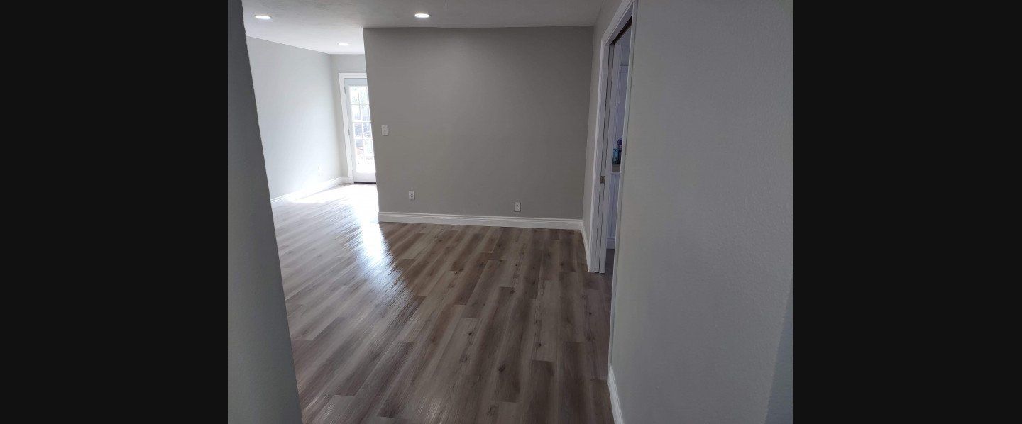A hallway in a house with hardwood floors and white walls.