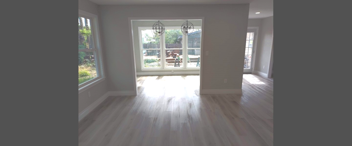An empty living room with hardwood floors and sliding glass doors.