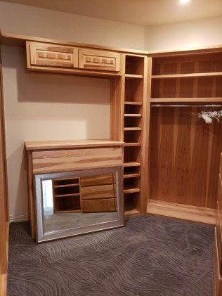 A walk in closet with wooden shelves and a mirror.