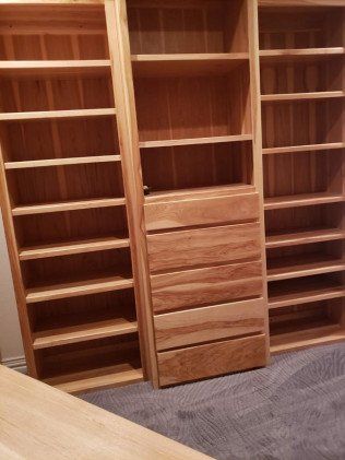 A closet with lots of wooden shelves and drawers