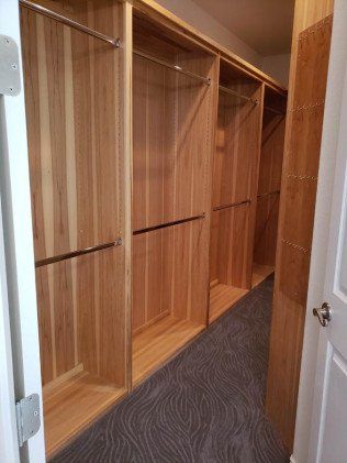 A walk in closet with lots of wooden shelves and clothes racks.