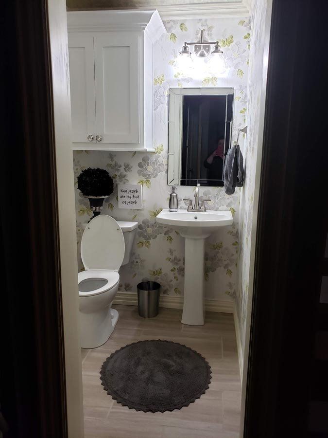 A bathroom with a toilet , sink and mirror.