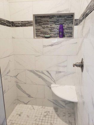 A bathroom with a walk in shower and a shelf.