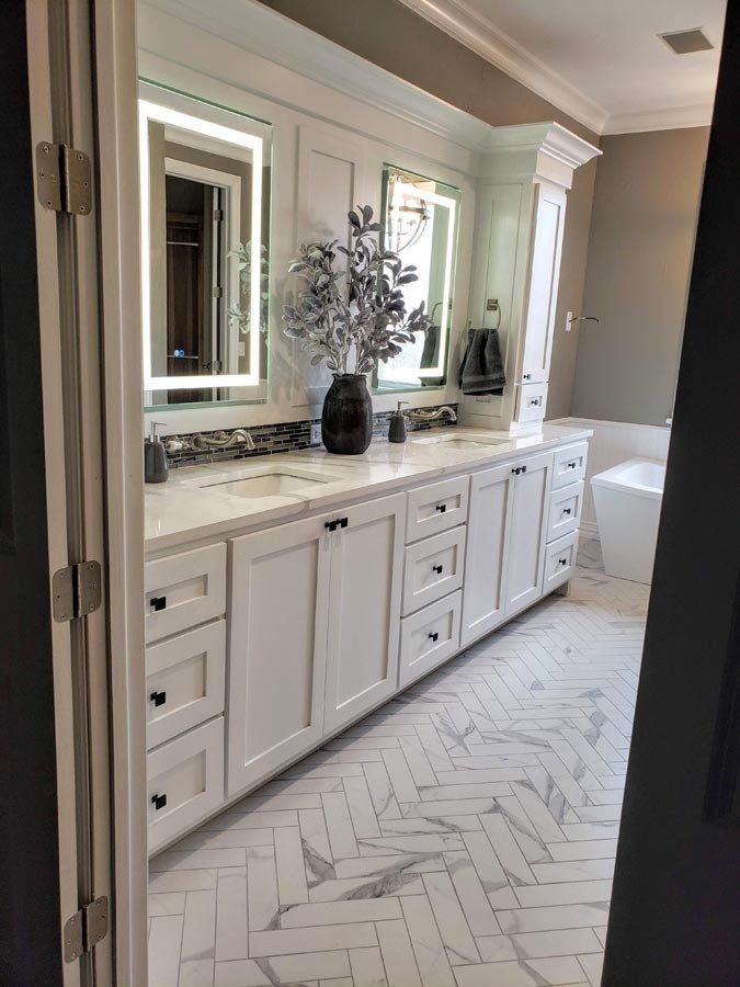 A bathroom with two sinks , two mirrors and a bathtub.