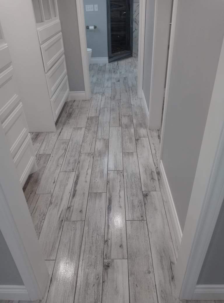 A hallway with a wooden floor and white walls.