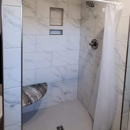 A bathroom with a walk in shower and a bench.