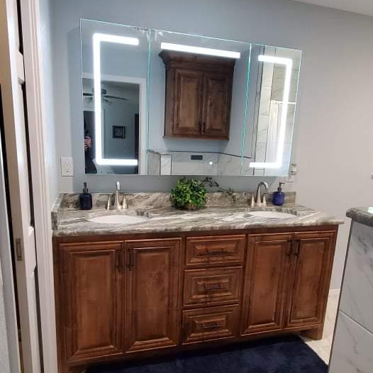 A bathroom with two sinks , a mirror and wooden cabinets.