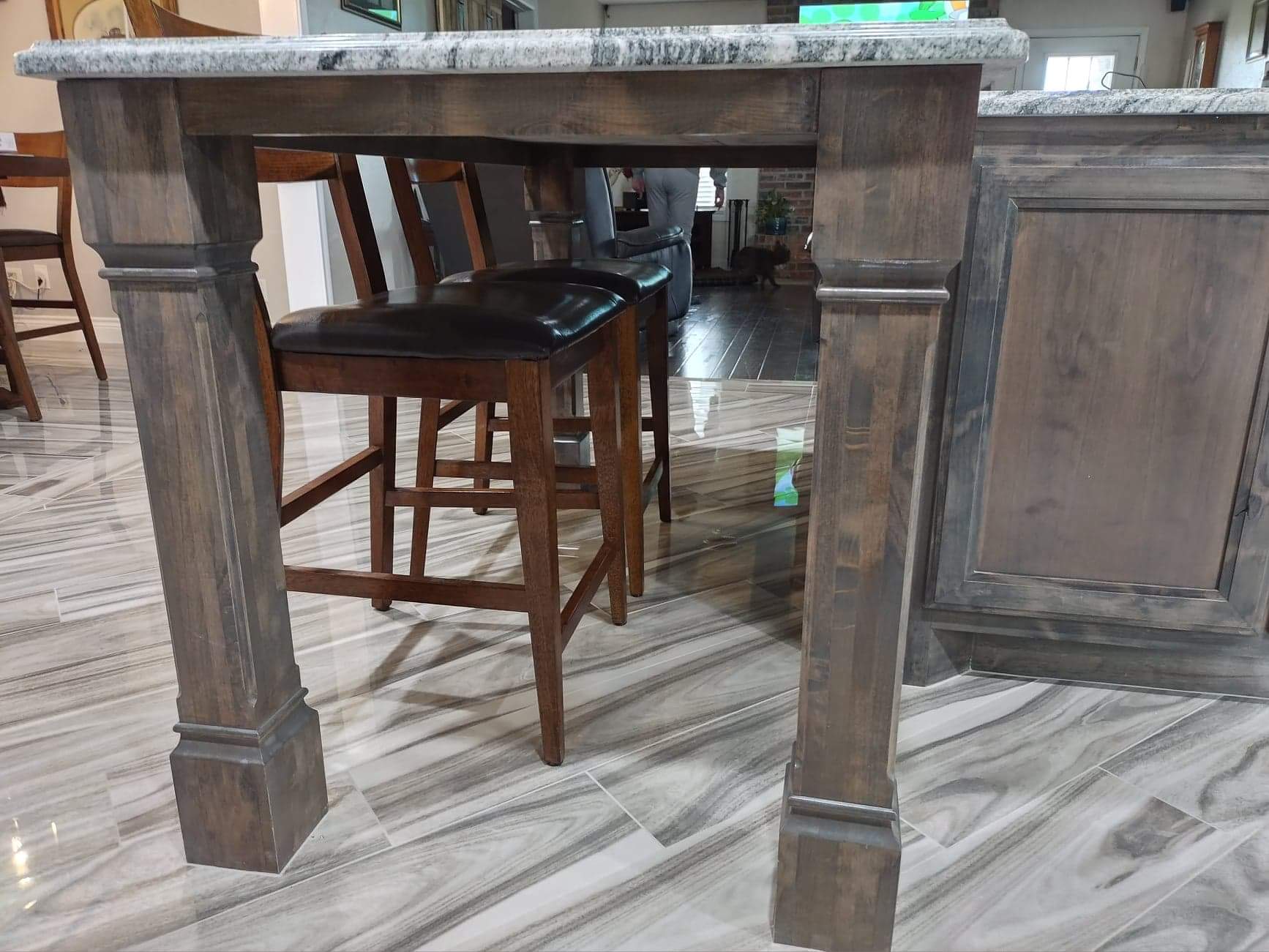 A kitchen island with a wooden table and stools underneath it.