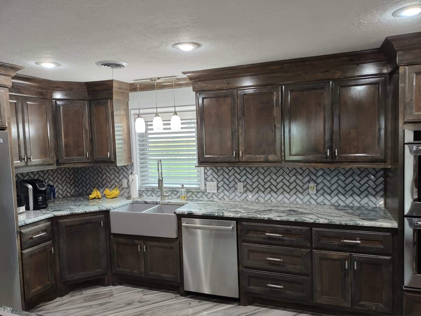 A kitchen with stainless steel appliances , wooden cabinets , granite counter tops and a sink.