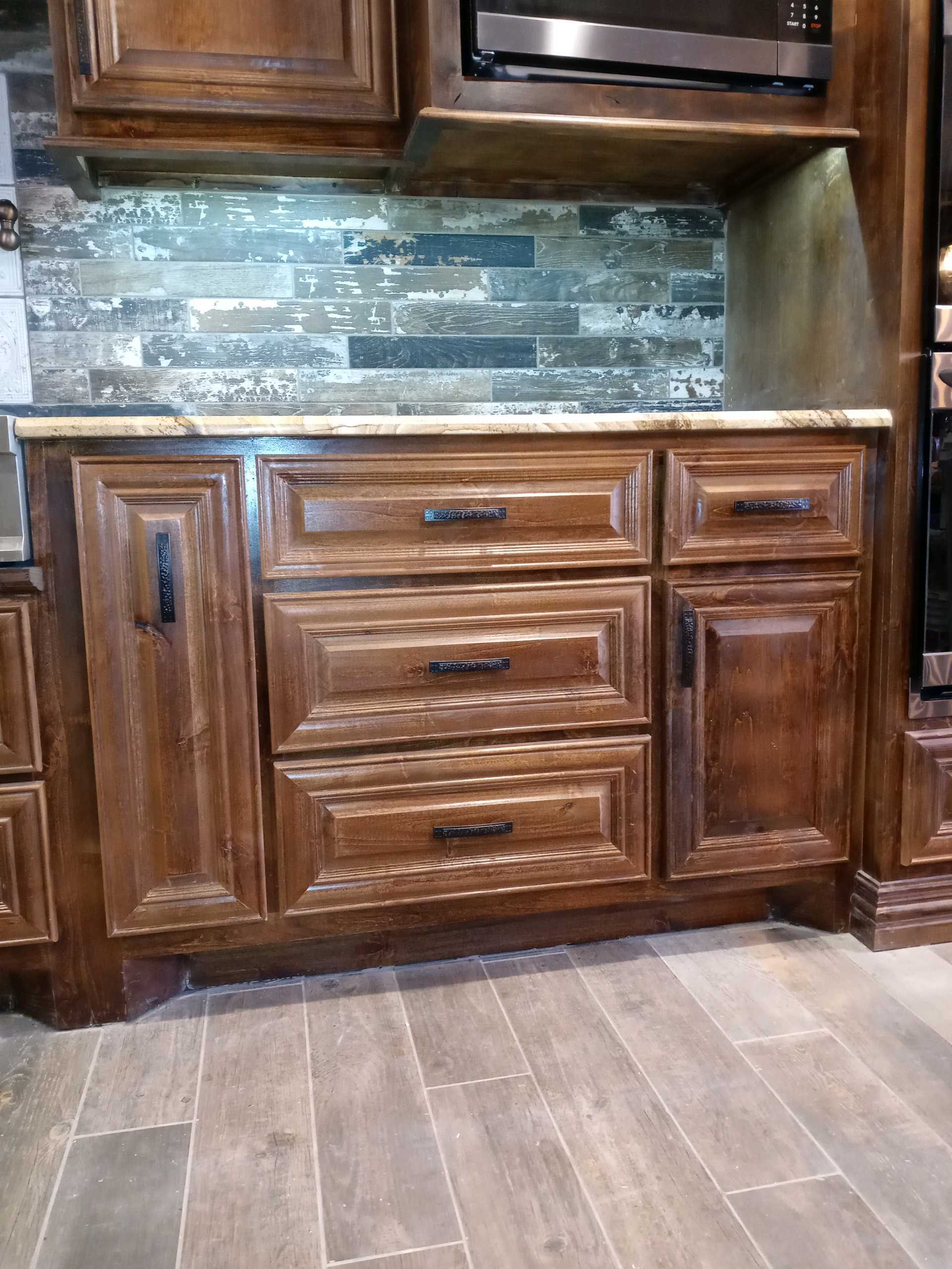 A kitchen with wooden cabinets , drawers , and a microwave.