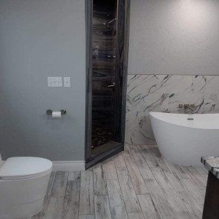 A bathroom with a toilet , tub and shower.