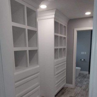 A walk in closet with lots of shelves and drawers.