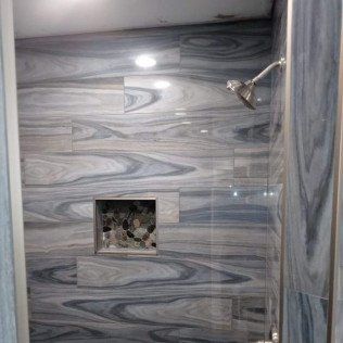 A bathroom with a shower head and a tiled wall.