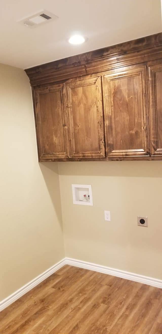 A room with hardwood floors and wooden cabinets on the wall.